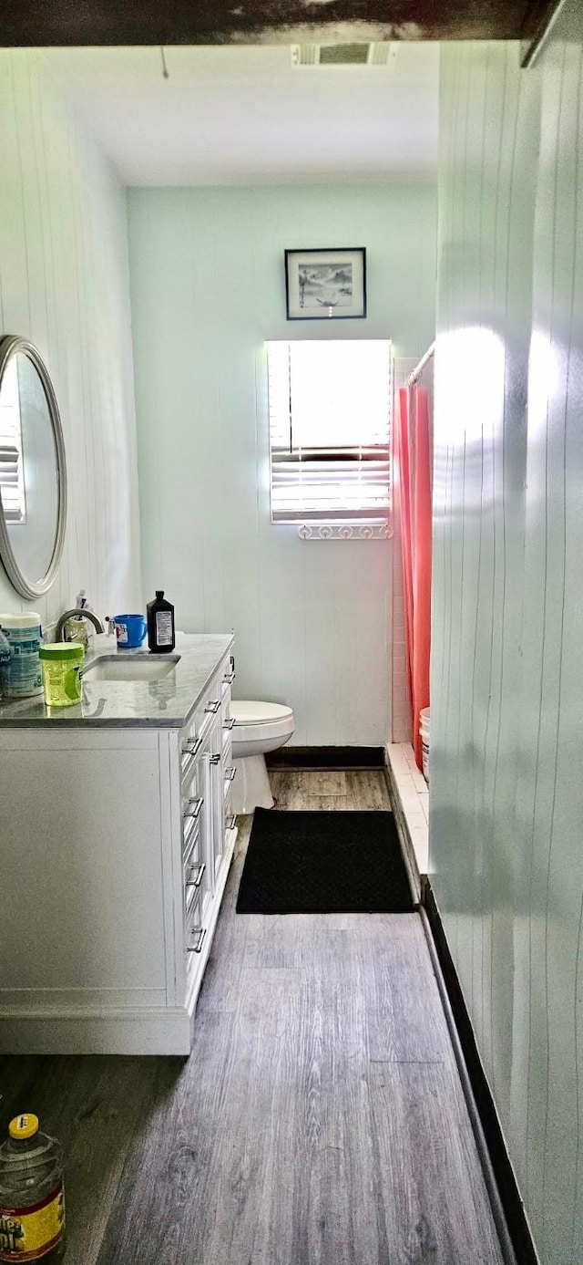 3137 18th St, Port Arthur, TX 77642 - bathroom featuring wood finished floors, vanity, toilet, a shower with curtain, and wood walls