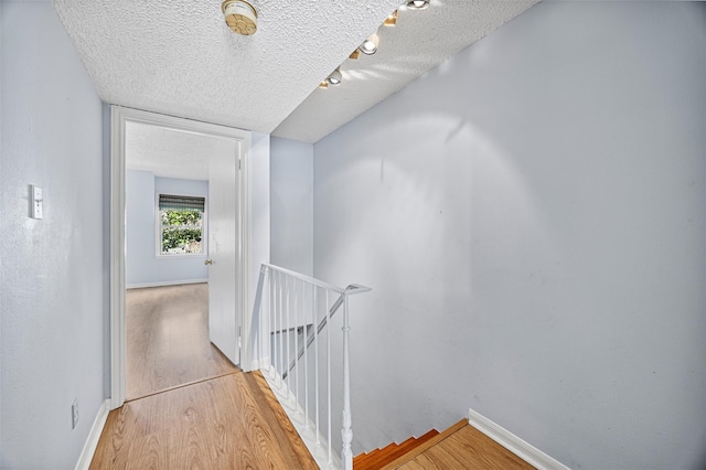 811 Lovett Blvd Unit 8, Houston, TX 77006 - hallway with an upstairs landing, a textured ceiling, light wood-type flooring, and baseboards