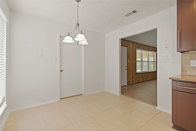 12839 Aste Ln, Houston, TX 77065 - unfurnished dining area with a chandelier, a textured ceiling, baseboards, and light tile patterned flooring