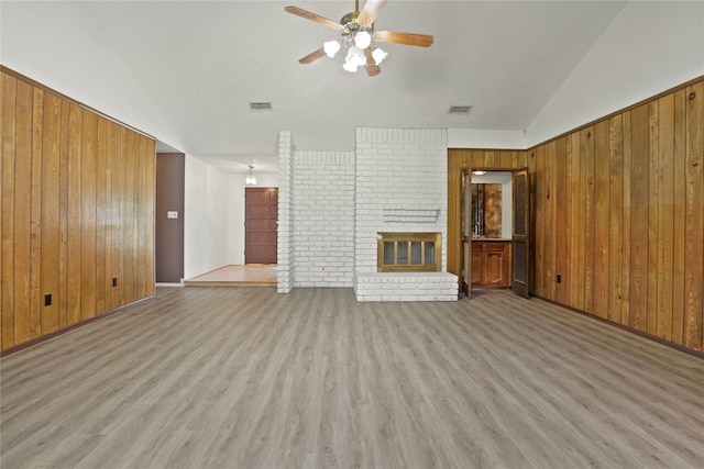 12839 Aste Ln, Houston, TX 77065 - unfurnished living room with wood walls, wood finished floors, a ceiling fan, a fireplace, and vaulted ceiling