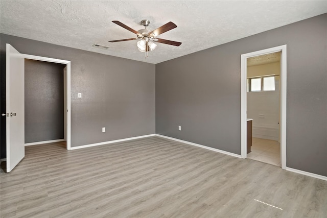 12839 Aste Ln, Houston, TX 77065 - unfurnished bedroom with wood finished floors, a textured ceiling, baseboards, ensuite bath, and ceiling fan