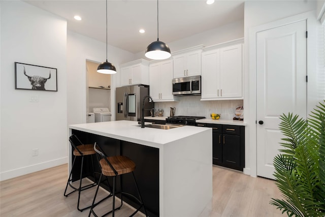 2522 Live Oak St, Houston, TX 77004 - kitchen with appliances with stainless steel finishes, a sink, tasteful backsplash, a center island with sink, and light wood-type flooring