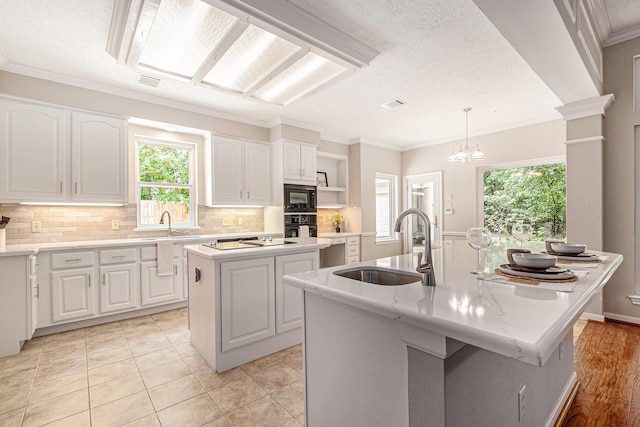 3506 Park Springs Ln, Houston, TX 77345 - kitchen featuring a kitchen island with sink, black appliances, a sink, white cabinetry, and crown molding