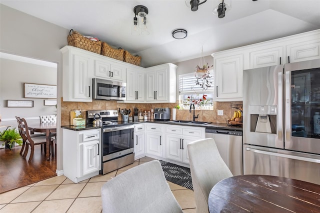 19715 Desna Dr, Porter, TX 77365 - kitchen featuring stainless steel appliances, a sink, dark countertops, light tile patterned floors, and backsplash