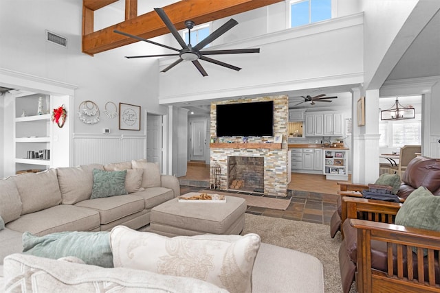 319 W Shore Dr, Kemah, TX 77565 - living room featuring high vaulted ceiling, ceiling fan, stone tile flooring, a fireplace, and a wainscoted wall
