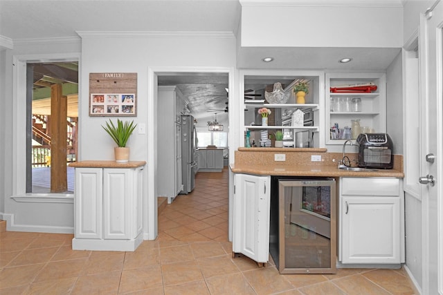 319 W Shore Dr, Kemah, TX 77565 - kitchen with beverage cooler, ornamental molding, white cabinets, freestanding refrigerator, and light tile patterned floors