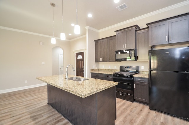 6523 Tuskegee St, Houston, TX 77091 - kitchen with black appliances, a sink, arched walkways, light wood finished floors, and an island with sink
