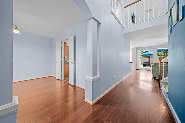 1802 Moston Dr, Spring, TX 77386 - hallway featuring arched walkways, wood finished floors, baseboards, stairway, and decorative columns