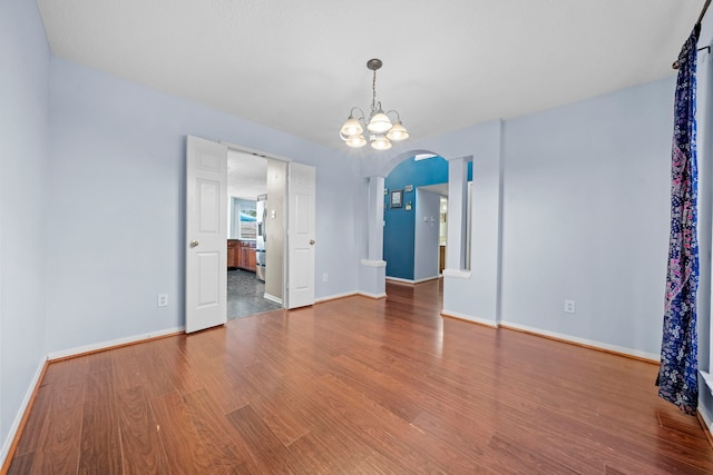 1802 Moston Dr, Spring, TX 77386 - empty room with arched walkways, wood finished floors, baseboards, and a chandelier