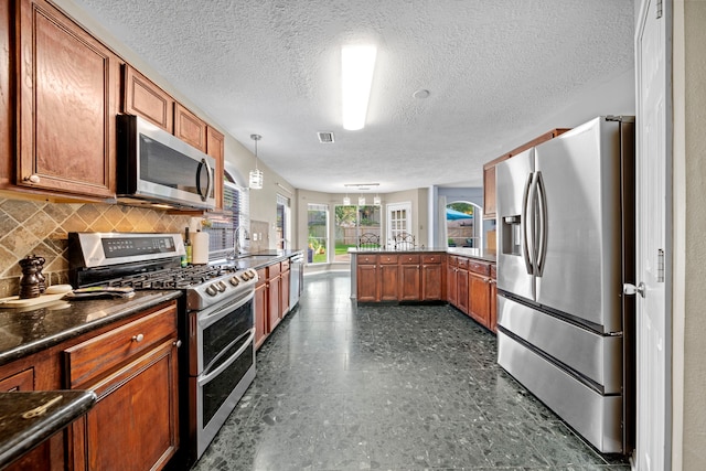 1802 Moston Dr, Spring, TX 77386 - kitchen with stainless steel appliances, a peninsula, a sink, brown cabinets, and dark countertops