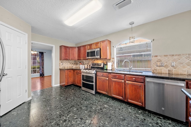 1802 Moston Dr, Spring, TX 77386 - kitchen featuring appliances with stainless steel finishes, a sink, dark countertops, tasteful backsplash, and a textured ceiling