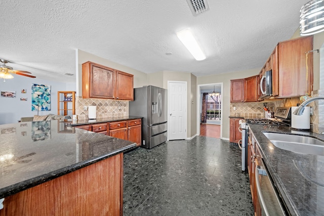 1802 Moston Dr, Spring, TX 77386 - kitchen with stainless steel appliances, a sink, backsplash, brown cabinetry, and a textured ceiling