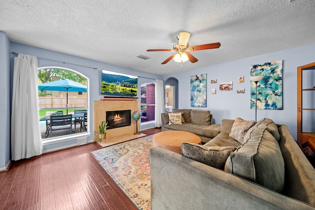 1802 Moston Dr, Spring, TX 77386 - living room featuring wood finished floors, a textured ceiling, a ceiling fan, a high end fireplace, and arched walkways