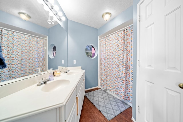 1802 Moston Dr, Spring, TX 77386 - bathroom featuring double vanity, wood finished floors, a textured ceiling, curtained shower, and baseboards