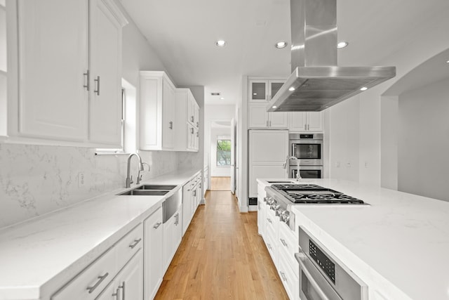 9714 Braesmont Dr, Houston, TX 77096 - kitchen featuring island exhaust hood, appliances with stainless steel finishes, a sink, recessed lighting, and white cabinetry