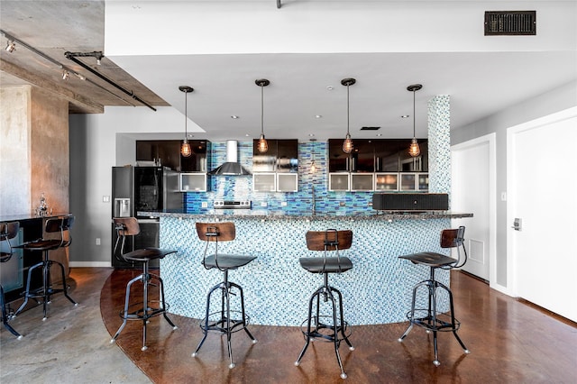 2000 Bagby St Unit 13430, Houston, TX 77002 - kitchen featuring wall chimney exhaust hood, concrete flooring, decorative backsplash, baseboards, and a breakfast bar