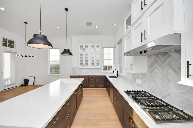 4005 Woodshire Village Ests, Houston, TX 77025 - kitchen featuring stainless steel gas cooktop, a center island, a sink, dark brown cabinetry, and white cabinets