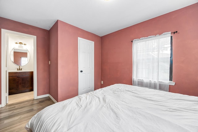 2915 Robertson St, Houston, TX 77009 - bedroom with wood finished floors, connected bathroom, baseboards, and a sink