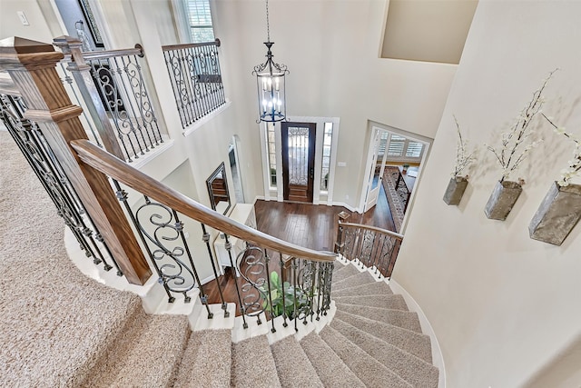 1013 Bolivar Point Ln, Friendswood, TX 77546 - entrance foyer with a chandelier, wood finished floors, a towering ceiling, stairway, and baseboards