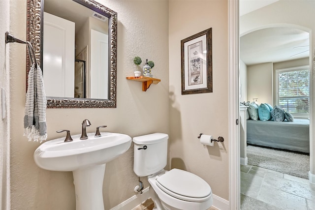 1013 Bolivar Point Ln, Friendswood, TX 77546 - bathroom featuring baseboards, toilet, stone tile flooring, and ensuite bathroom