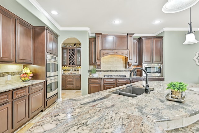 1013 Bolivar Point Ln, Friendswood, TX 77546 - kitchen featuring a sink, ornamental molding, stainless steel appliances, light stone counters, and pendant lighting