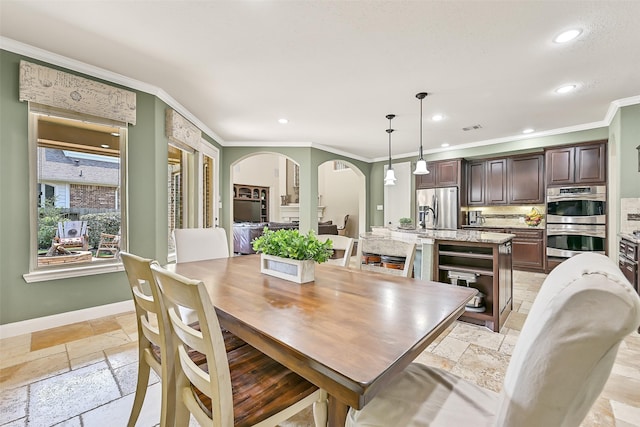1013 Bolivar Point Ln, Friendswood, TX 77546 - dining room with stone tile flooring, ornamental molding, arched walkways, recessed lighting, and baseboards