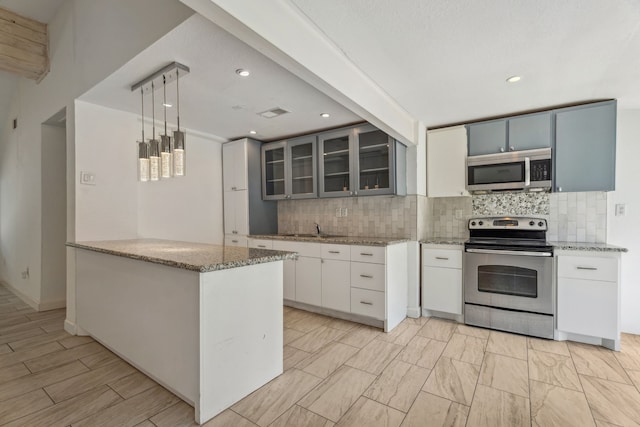 6414 Crestridge St, Houston, TX 77033 - kitchen featuring stainless steel appliances, backsplash, glass insert cabinets, light stone counters, and recessed lighting