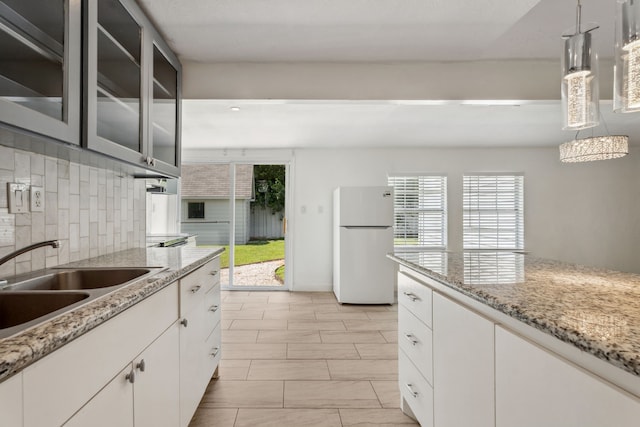 6414 Crestridge St, Houston, TX 77033 - kitchen featuring freestanding refrigerator, tasteful backsplash, glass insert cabinets, hanging light fixtures, and a sink