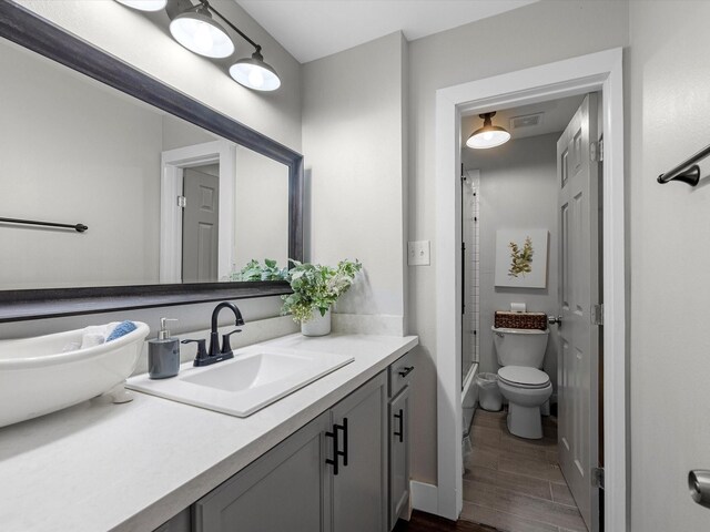14510 Henry Calfee Dr, Willis, TX 77318 - bathroom with vanity, wood finished floors, toilet, and combined bath / shower with glass door