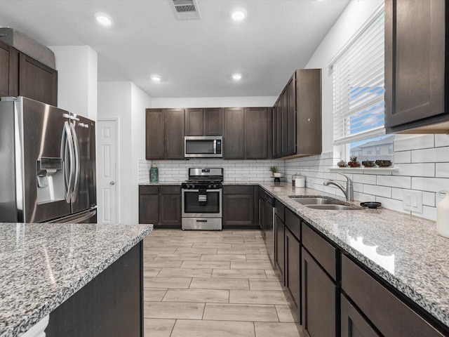15618 Cliffside Arbor Ln, Houston, TX 77044 - kitchen with appliances with stainless steel finishes, a sink, light stone countertops, decorative backsplash, and recessed lighting