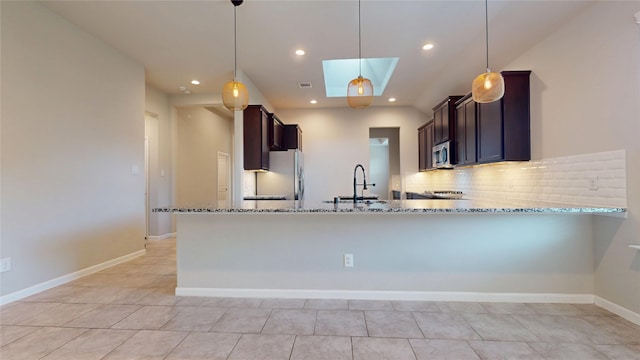 5434 Wildbrush Dr, Richmond, TX 77407 - kitchen featuring appliances with stainless steel finishes, a sink, stone countertops, tasteful backsplash, and a skylight