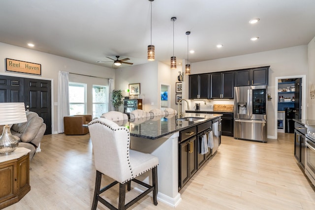 454 Cape Conroe Dr, Montgomery, TX 77356 - kitchen featuring stainless steel fridge with ice dispenser, a sink, a breakfast bar area, light wood finished floors, and recessed lighting