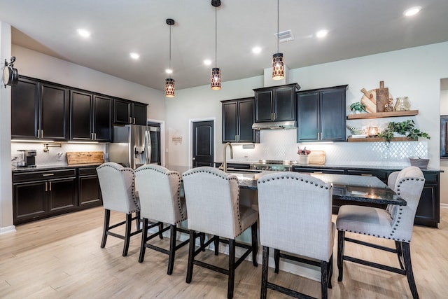 454 Cape Conroe Dr, Montgomery, TX 77356 - kitchen featuring stainless steel fridge with ice dispenser, backsplash, a breakfast bar area, dark stone countertops, and light wood-style flooring
