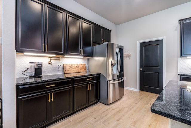 454 Cape Conroe Dr, Montgomery, TX 77356 - kitchen featuring stainless steel refrigerator with ice dispenser, dark stone counters, decorative backsplash, light wood-style floors, and dark cabinets