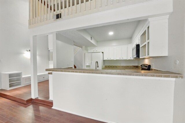 3126 Windchase Blvd Unit 421, Houston, TX 77082 - kitchen with white fridge with ice dispenser, stainless steel microwave, a peninsula, dark wood-type flooring, and tile countertops