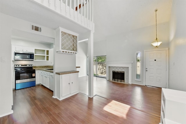 3126 Windchase Blvd Unit 421, Houston, TX 77082 - kitchen with stainless steel appliances, a high ceiling, dark wood finished floors, white cabinets, and pendant lighting