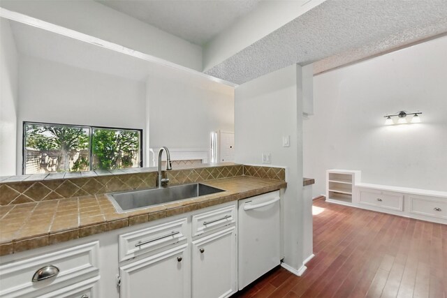 3126 Windchase Blvd Unit 421, Houston, TX 77082 - kitchen featuring white dishwasher, a sink, backsplash, dark wood-type flooring, and white cabinetry