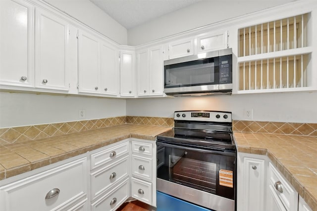 3126 Windchase Blvd Unit 421, Houston, TX 77082 - kitchen featuring stainless steel appliances, white cabinetry, tile counters, and open shelves