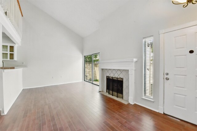 3126 Windchase Blvd Unit 421, Houston, TX 77082 - unfurnished living room with high vaulted ceiling, a tiled fireplace, wood finished floors, and baseboards