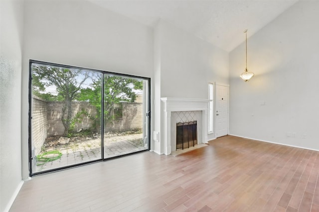 3126 Windchase Blvd Unit 421, Houston, TX 77082 - unfurnished living room featuring a towering ceiling, wood finished floors, a tiled fireplace, and baseboards