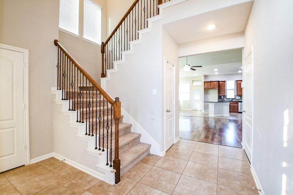 6406 Hunters Way Ln, Baytown, TX 77521 - stairs with a ceiling fan, tile patterned flooring, and a towering ceiling
