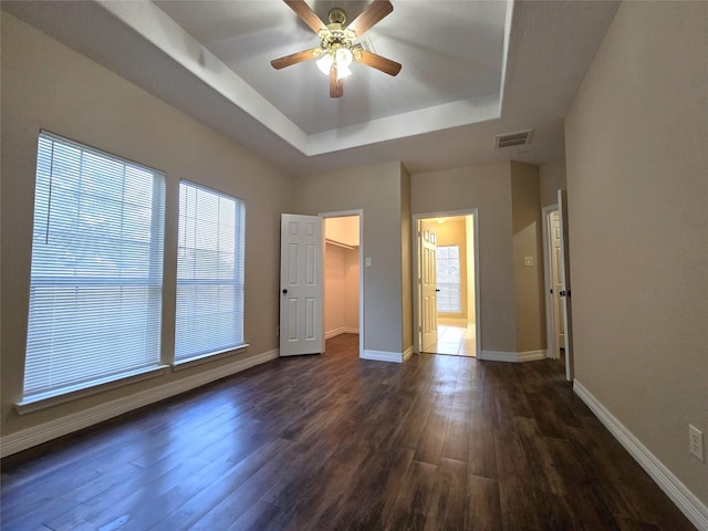 1944 Hillcroft, Prairie View, TX 77445 - unfurnished bedroom featuring a raised ceiling, dark wood-type flooring, baseboards, a spacious closet, and ceiling fan