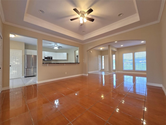1944 Hillcroft, Prairie View, TX 77445 - unfurnished living room with a ceiling fan, arched walkways, light tile patterned flooring, a tray ceiling, and baseboards