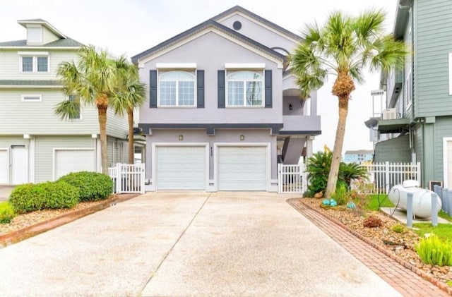 423 Hana Dr, Tiki Island, TX 77554 - townhome / multi-family property featuring stucco siding, concrete driveway, a garage, and a gate