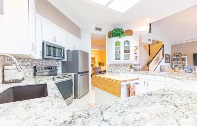 423 Hana Dr, Tiki Island, TX 77554 - kitchen with stainless steel appliances, light stone countertops, a sink, decorative backsplash, and white cabinets
