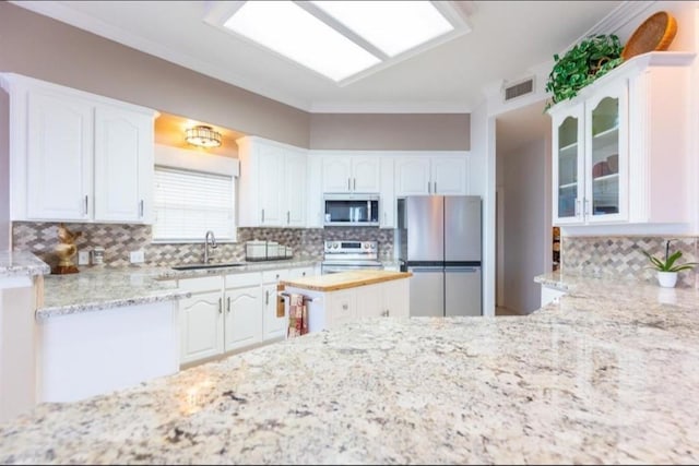 423 Hana Dr, Tiki Island, TX 77554 - kitchen with stainless steel appliances, a sink, light stone countertops, tasteful backsplash, and white cabinets