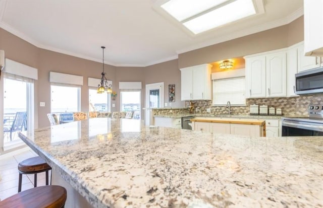 423 Hana Dr, Tiki Island, TX 77554 - kitchen with stainless steel appliances, a breakfast bar area, decorative backsplash, light stone counters, and crown molding