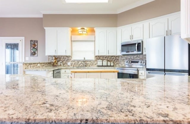 423 Hana Dr, Tiki Island, TX 77554 - kitchen with appliances with stainless steel finishes, a sink, crown molding, light stone counters, and decorative backsplash