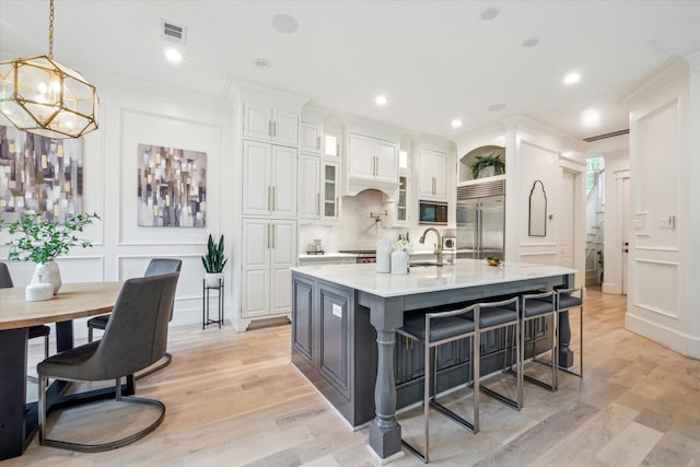 432 Marshall St, Houston, TX 77006 - kitchen featuring built in appliances, light countertops, a chandelier, white cabinetry, and a kitchen bar