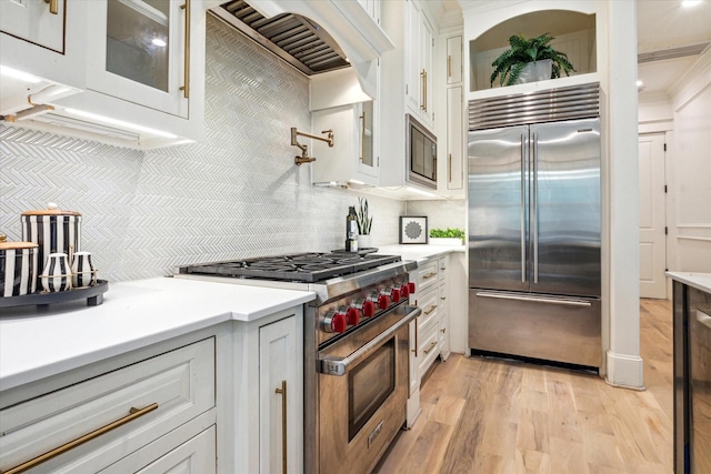 432 Marshall St, Houston, TX 77006 - kitchen with built in appliances, glass insert cabinets, tasteful backsplash, light wood-type flooring, and light countertops